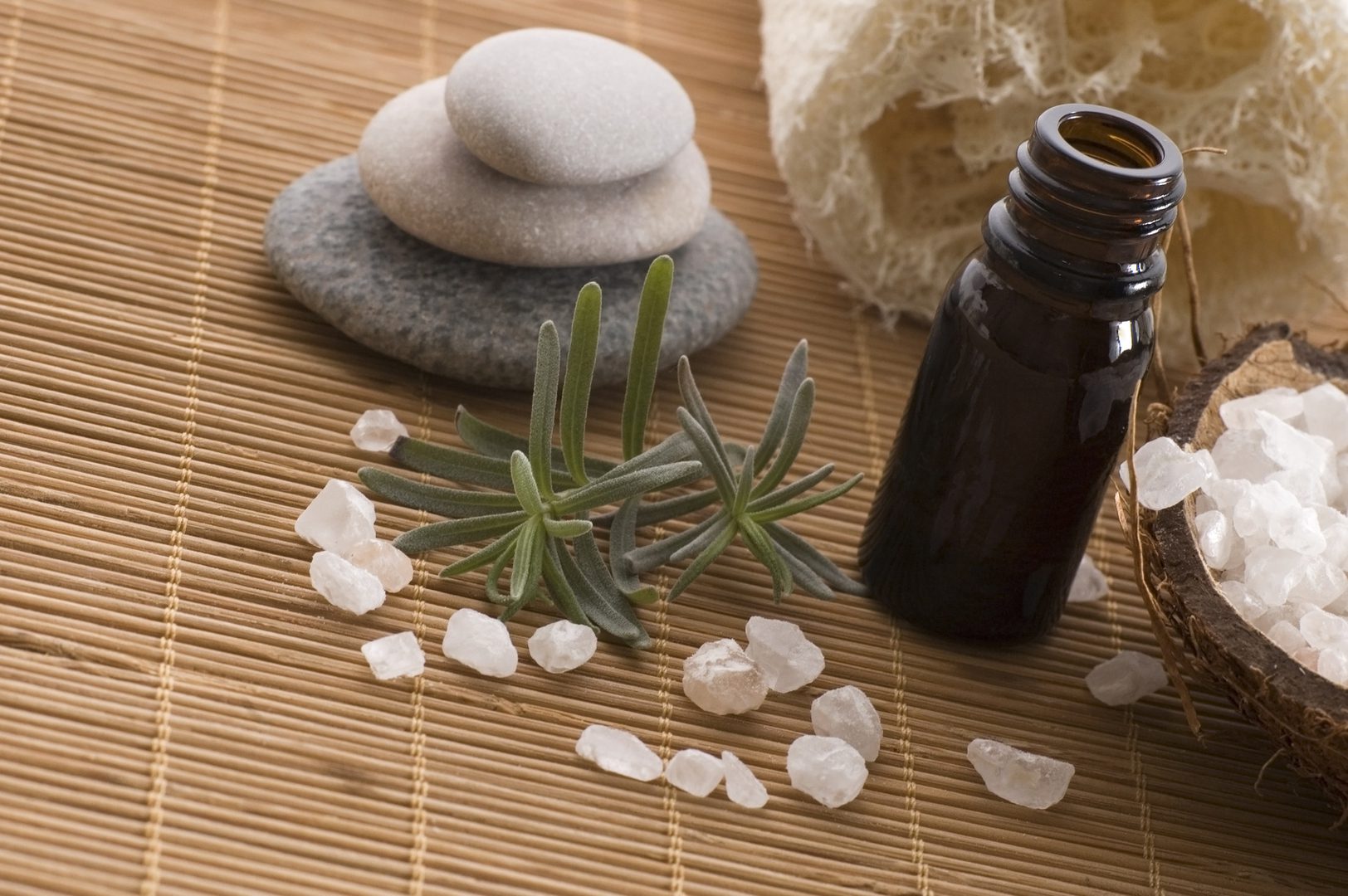 A bottle of essential oil and some rocks on the floor.